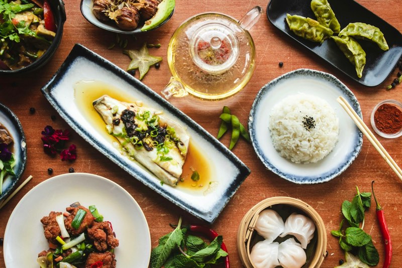 Table filled with Chinese dishes, dumplings, rice and dim sum