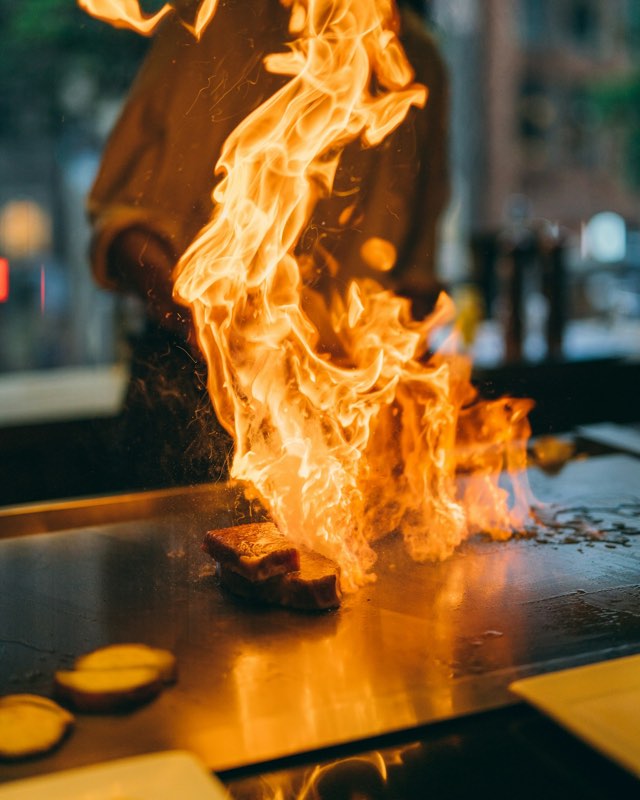 Steak searing in tall flames on a hibachi grill