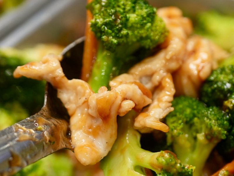 Chicken and broccoli in brown sauce lifted on a serving spoon