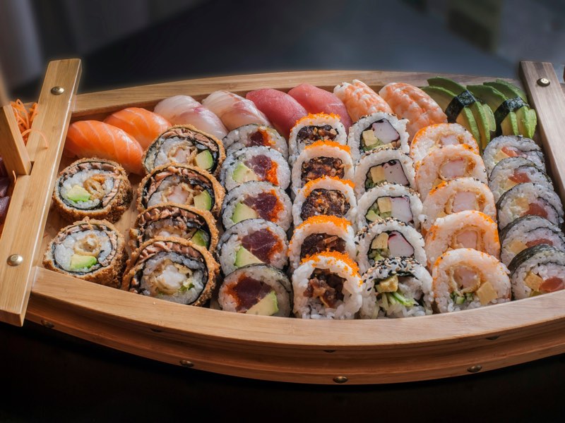 Wooden sushi boat filled with assorted sushi rolls